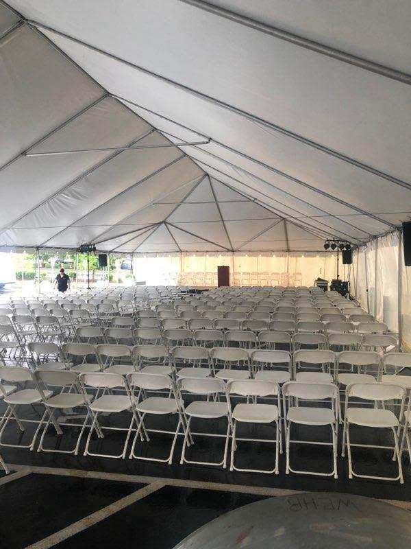 Tent interior with rows of white folding chairs