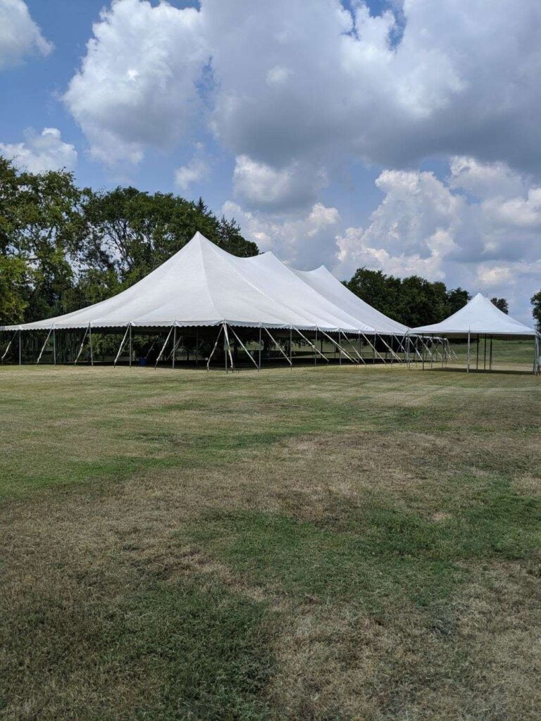 White peaked tent in grassy field
